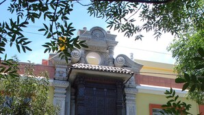 Un edificio con una entrada decorativa, un arco de piedra y una reja de metal.