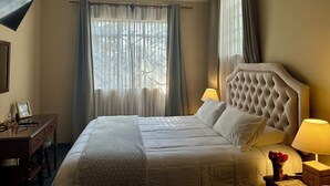 Una habitación de hotel con una cama grande, un escritorio, una lámpara y un jarrón con flores.