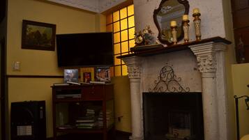 Una habitación con chimenea, televisor y estanterías.