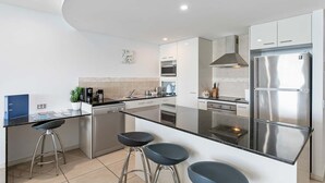 A modern kitchen with a central island, stainless steel appliances, and bar stools.