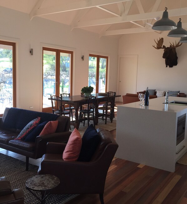 A spacious living area with a sofa, chairs, a dining table, and a kitchen island.
