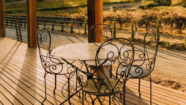 Eine Holzterrasse mit Tisch und Stühlen mit Blick auf einen Weinberg.
