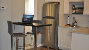 A modern kitchen with a stainless steel refrigerator, a laptop on a bar counter, and a sink with a faucet. - New Loft w/South River view from treehouse deck! (Riva)