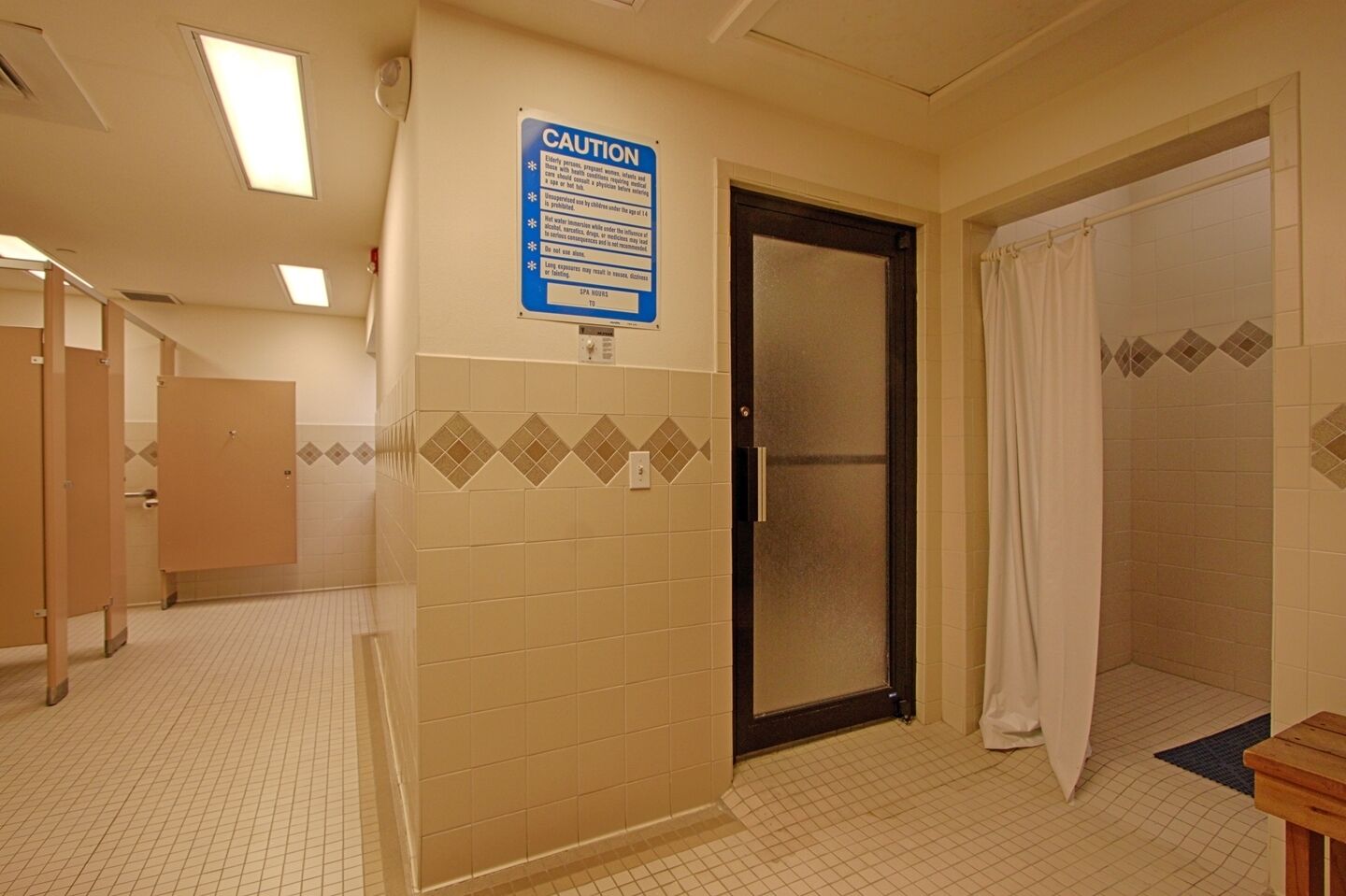 Un baño con un letrero de precaución, una puerta y una cortina de ducha.