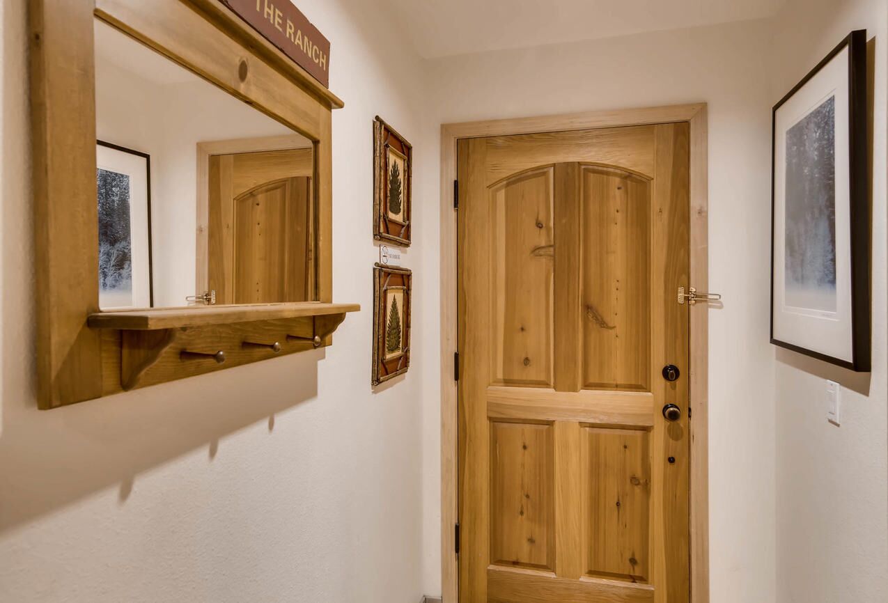 Eine Holztür mit einem Spiegel darüber, ein Regal mit gerahmten Bildern und ein Schild über der Tür.
