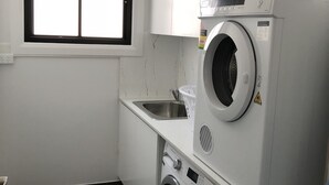 A laundry room with a washing machine, a dryer, a sink, and a window.