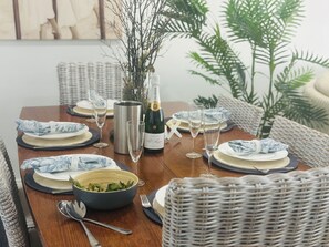 A dining table set with plates, cutlery, glasses, a bottle of champagne, and a bowl of salad. - U2 at Moana Beach Esplanade • Exclusive 2 Bdrm Apt • WiFi • Spa • Pet Friendly (Moana)
