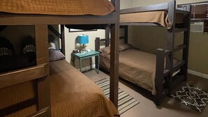 Una camera con letto a castello, una ventola a soffitto, un tavolino con lampada e una radio.