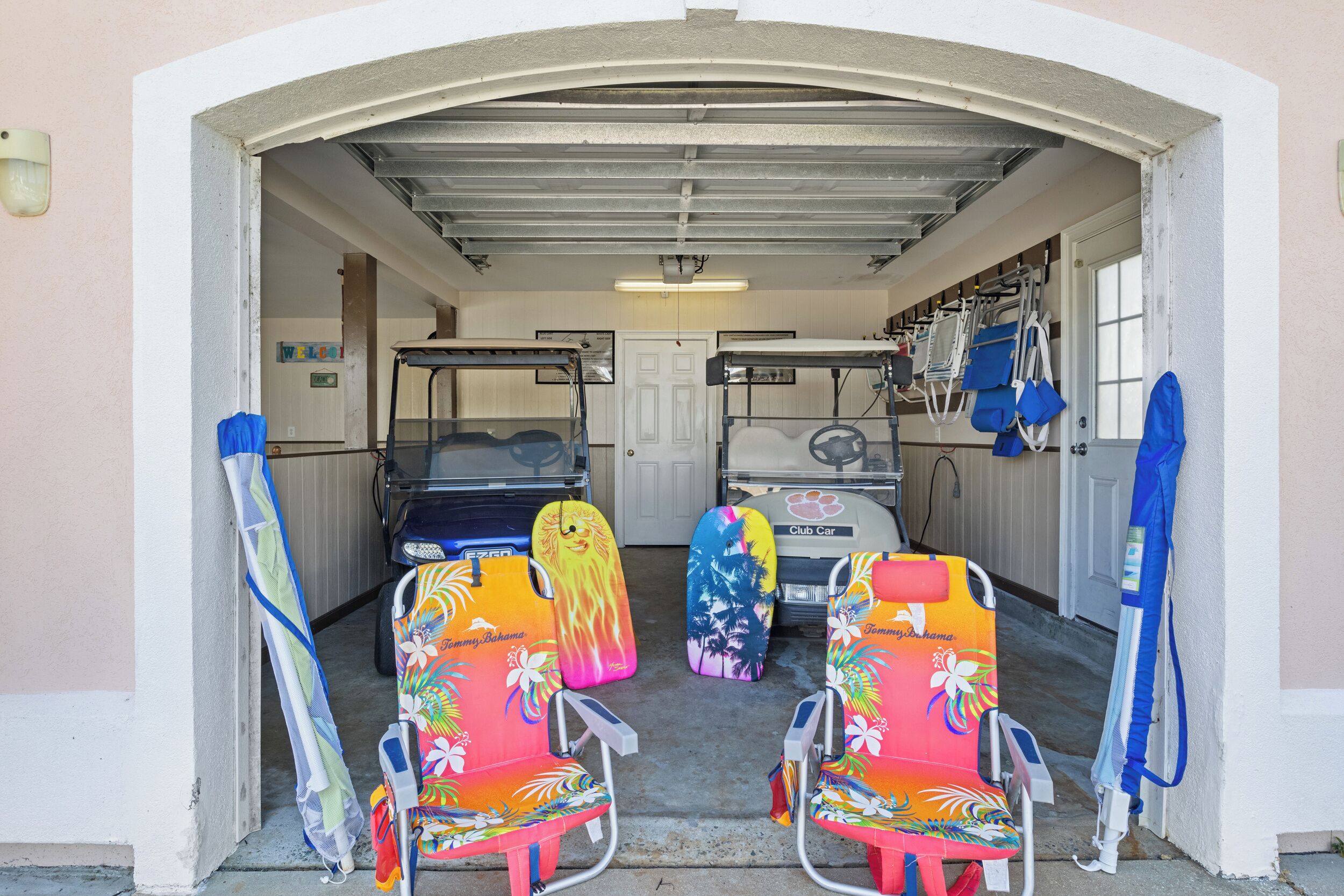 Een garage met twee kleurrijke strandstoelen en een Club Car erin geparkeerd.