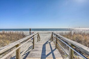 A wooden boardwalk leading to a beach with clear skies.