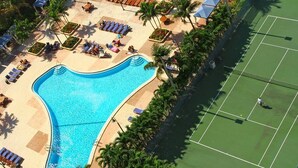 Oversigtsbillede af et resort med swimmingpool, tennisbaner og loungeområder.