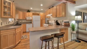 A kitchen with wooden cabinets, a central island with stools, a microwave, a refrigerator, and a stove. - The Barn house - 1.5 miles to Whiskey Row (Prescott)