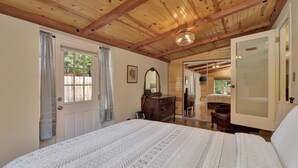 A bedroom with a wooden ceiling, a large bed, a dresser, and a mirror. - The Barn house - 1.5 miles to Whiskey Row (Prescott)