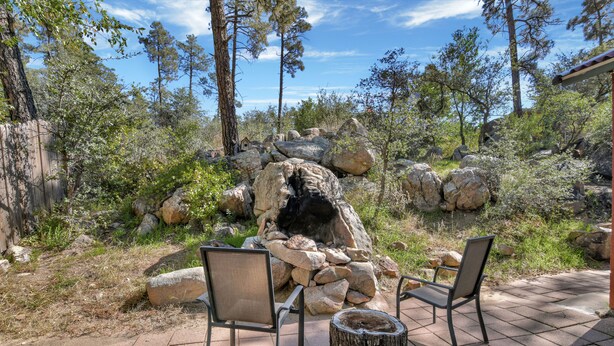 An outdoor patio with two chairs and a wooden stump table, surrounded by rocks and trees. - The Barn house - 1.5 miles to Whiskey Row (Prescott)