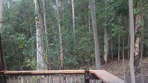 Une terrasse en bois avec une rambarde en métal, une table en métal et une chaise en métal.