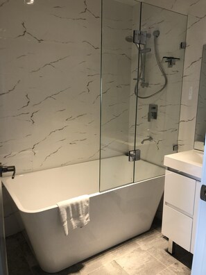 Bañera con ducha, toallas, papel higiénico