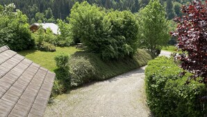 A mountain view from a wooden deck with a gravel path leading to a house.