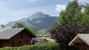 A rustic wooden building with a sloped roof, surrounded by lush greenery and a gravel path.