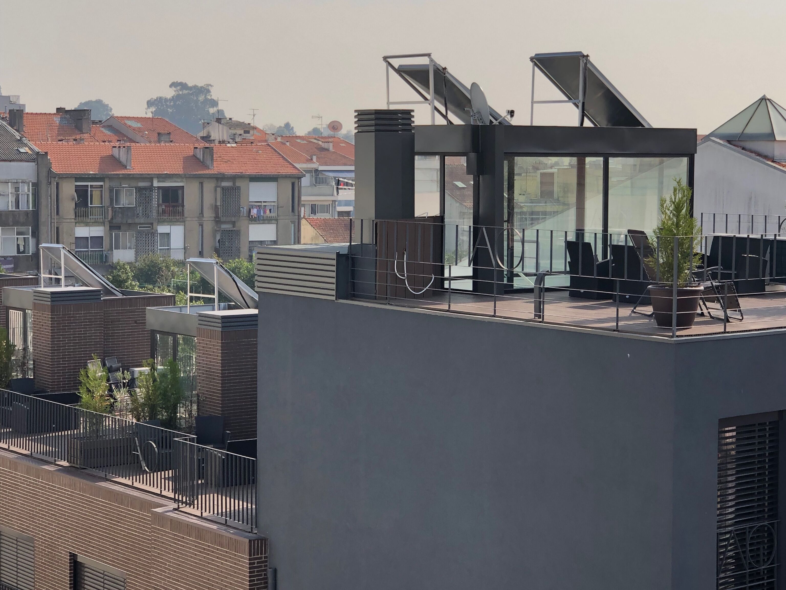 Eine Dachterrasse im modernen Stil mit Glasumrandung, Sitzgelegenheiten und Solaranlage.