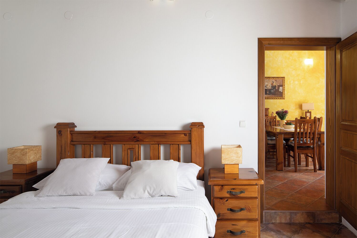 Une chambre à coucher avec un lit en bois, des tables de chevet et une petite commode en bois.