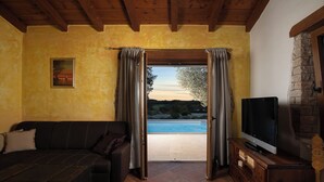 A living room with a sofa, a television, and a view of a swimming pool. - LUX CASA HISTRIA I - with heated swimming pool & jacuzzi (Pazin)