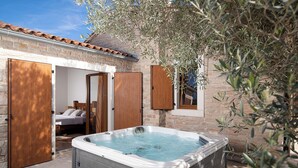 A spa area with a hot tub, wooden doors, and a bed visible through an open door. - LUX CASA HISTRIA I - with heated swimming pool & jacuzzi (Pazin)
