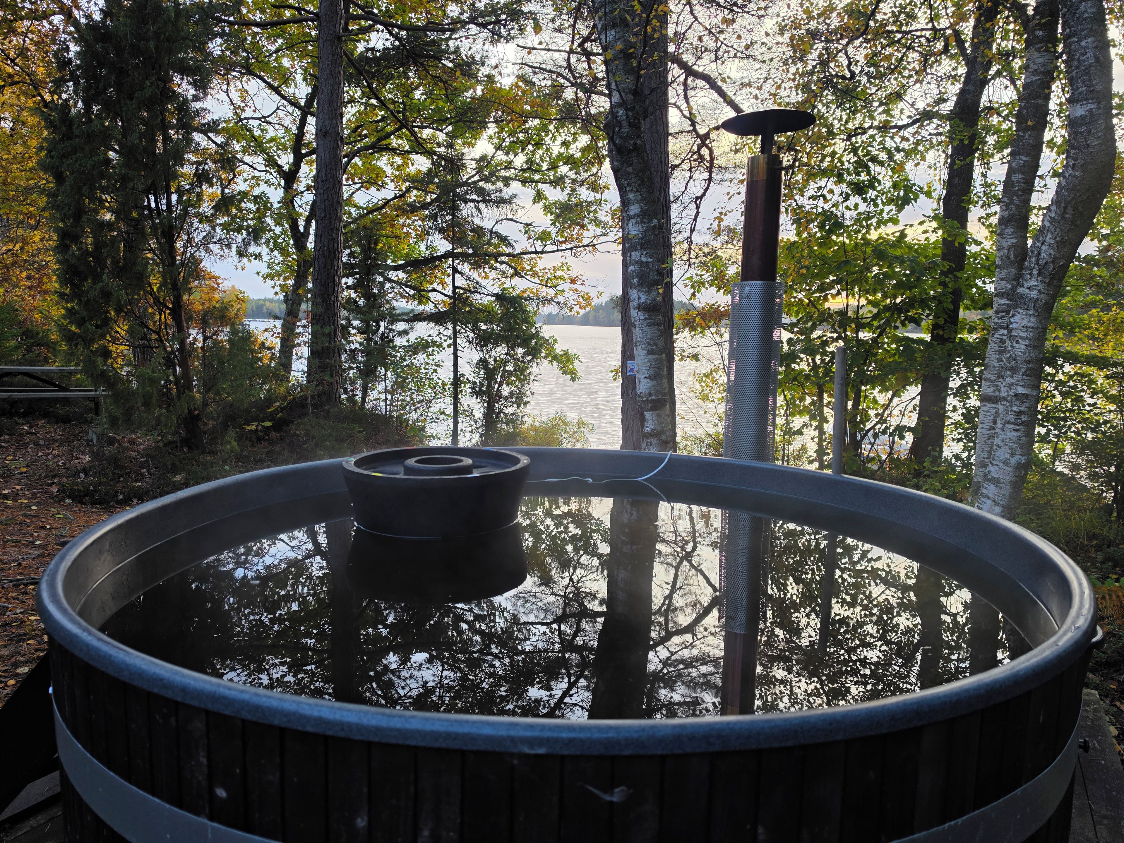 Een hottub omringd door bomen met uitzicht op een meer.