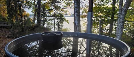 Een hottub omringd door bomen met uitzicht op een meer.