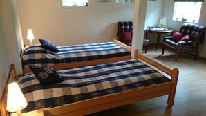 A room with two wooden beds with checkered bedding, a small table, and a chair. - Cozy cottage near the lake, including free Wi-Fi and own rowing boat (Hallaryd)