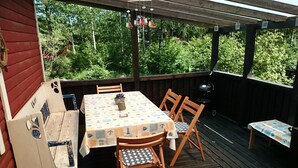 A covered outdoor patio with a table and chairs, a grill, and a wooden deck. - Cozy cottage near the lake, including free Wi-Fi and own rowing boat (Hallaryd)