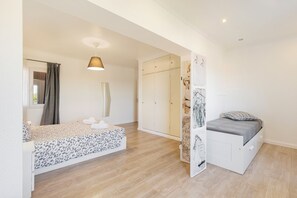 Quarto com cama, mesa de cabeceira, guarda-roupa e espaço para chuveiro.