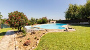 A backyard with a swimming pool, a paved walkway, and a variety of plants and trees. - Lovely Farm with Pool @30min Lisbon and Beaches (Palmela)
