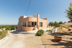 Uma casa moderna com telhado curvo, varanda e entrada com calçada.