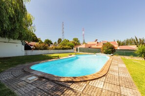 Enjoy a refreshing swim in the pool surrounded by a serene outdoor space with lush greenery.