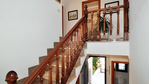 Una escalera de madera de varios niveles con barandilla que conduce a un rellano con una puerta al exterior.