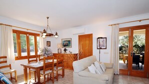Una sala de estar con sofá, mesa de comedor, sillas y una araña.