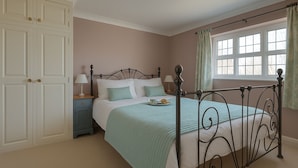 A bedroom with a bed, a nightstand, a wardrobe, and a window with curtains. - Little Chequers is a pretty pet friendly cottage , sleeps 3. close to Aldeburgh (Friston)