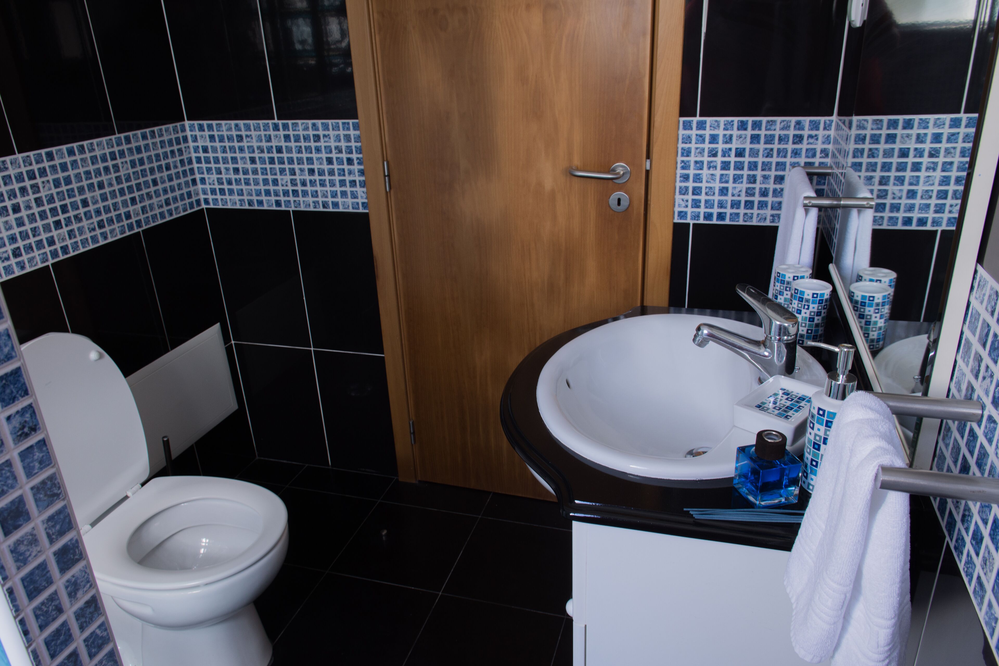 A bathroom with a toilet, sink, and mirror.
