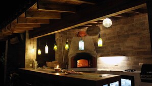 Une cuisine rustique avec un mur en briques, des suspensions décoratives et un poêle à bois.