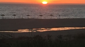 Una playa con sombrillas y un atardecer.