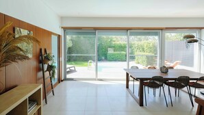 Un comedor moderno con una mesa grande y sillas, un banco de madera y una planta en un escalón.