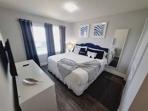 Quarto de hotel bem arrumado com cama, mesa de cabeceira e espelho.