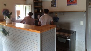 Cucina con piani di lavoro in legno, forno a gas in acciaio inossidabile e pensile per pentole.