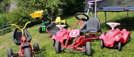A grassy area with various children's tricycles and a scooter.