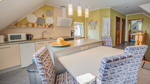 A kitchen with a dining area, including a microwave, sink, and a large island with chairs. - Comfortable apartment with panoramic views of the Giant Mountains (Jezów Sudecki)