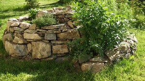 A stone garden bed with lush greenery and a small tree. - Comfortable apartment with panoramic views of the Giant Mountains (Jezów Sudecki)