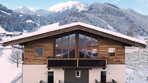 A wooden chalet with a sloped roof, large windows, and a stone foundation.