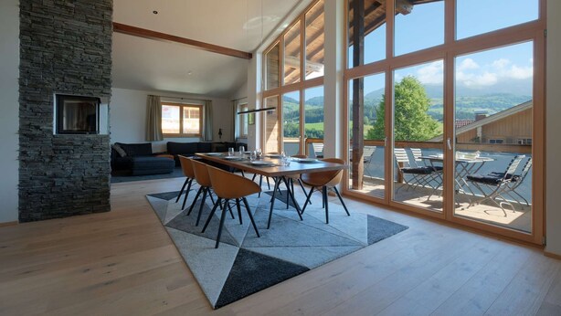 A spacious living area with a dining table, chairs, and a stone accent wall.