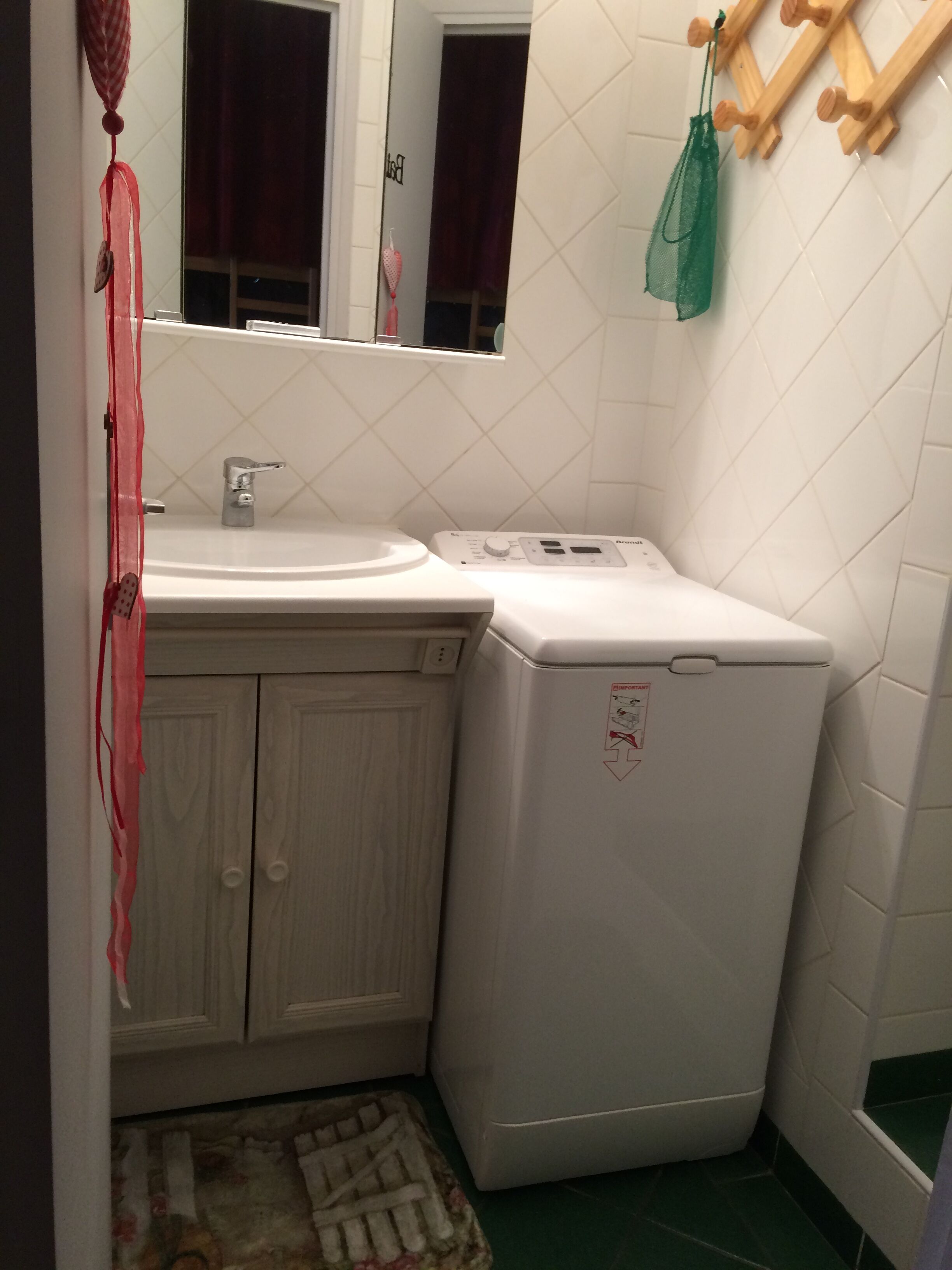 A compact bathroom with a white sink, a toilet, and a washing machine.