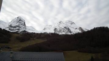 Un paysage de montagne avec des sommets enneigés et, au premier plan, un bâtiment doté d’un toit en métal.
